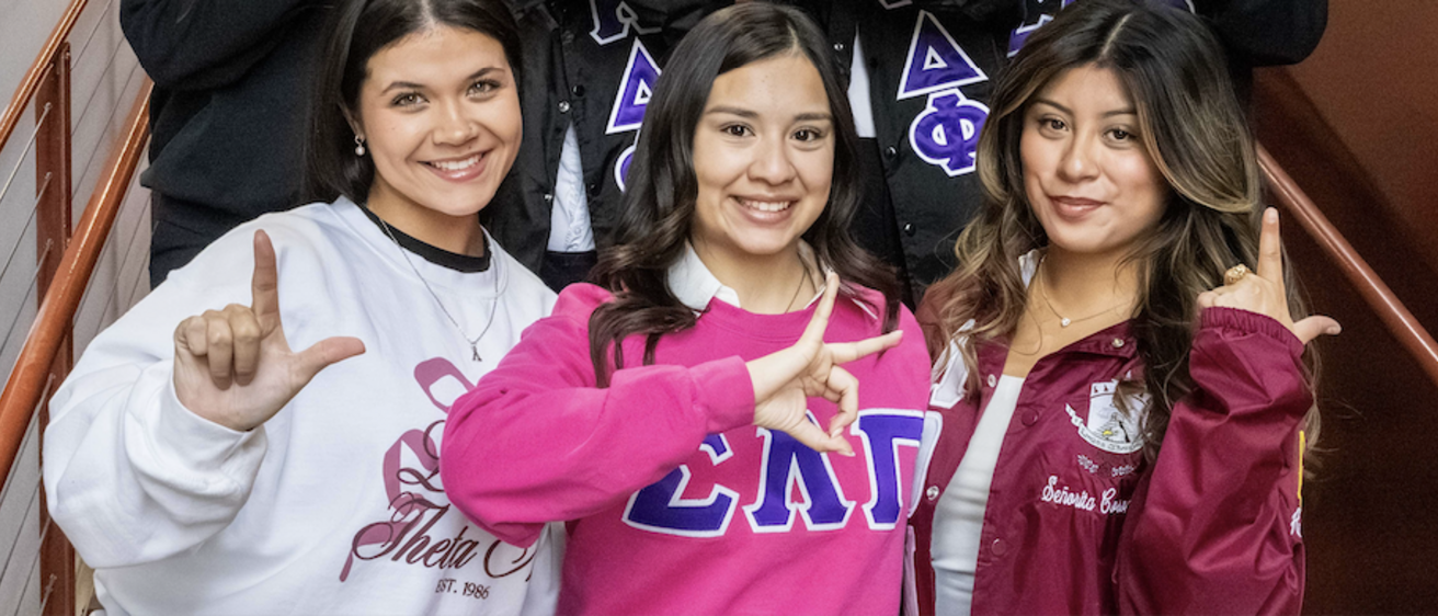 Students wearing Greek letter shirts posing in stairwell